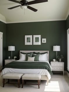 a bedroom with green walls and white bedding, two framed pictures on the wall