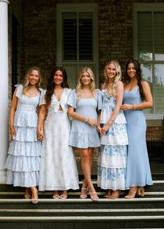 four women standing on steps in dresses