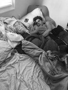 a black and white photo of a man laying in bed with his head on the pillow