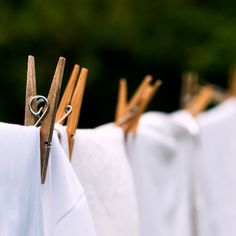 wooden clothes pins are hanging on the clothesline with white linens in front of them