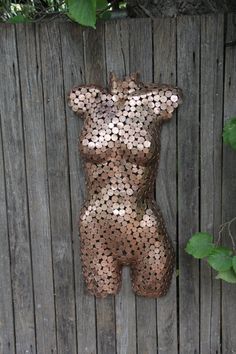 a statue made out of coins sitting on top of a wooden fence