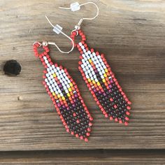 a pair of beaded earrings sitting on top of a wooden table