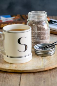 a cup of coffee sitting on top of a wooden table next to a cookie tin