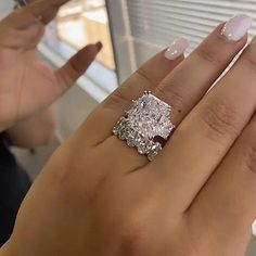 a woman's hand with a diamond ring on it and the other hand holding an engagement ring