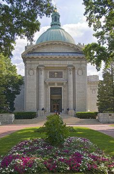 a large building with a dome on top and flowers in the foreground around it