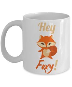 a white coffee mug with an orange fox saying hey, faxy on it