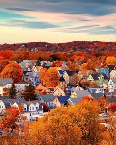 a city with lots of houses and trees in the foreground, surrounded by fall foliage