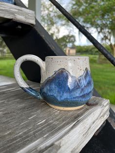 a blue and white mug sitting on top of a wooden bench