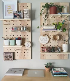 two wooden pegboard shelves with plants, books and other office supplies on top of them