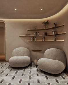 two chairs and a table in a room with shelving on the wall behind them