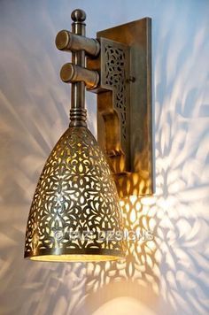 a wall light that is hanging on the side of a wall with an intricate design