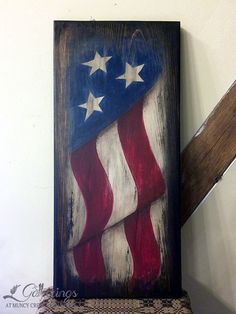 an american flag is painted on a wooden frame above a chair in a room with white walls