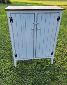 an old white cabinet sitting in the grass