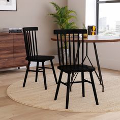 two black chairs sitting on top of a rug in front of a table with a potted plant