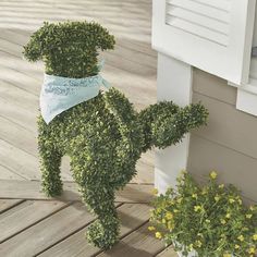 there is a fake dog made out of plants on the porch with flowers in front of it