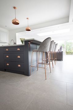 a modern kitchen with bar stools and an island in the middle is pictured here