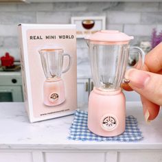 a pink blender sitting on top of a kitchen counter next to a boxed box