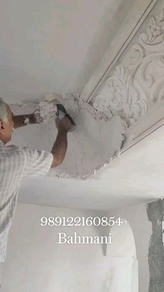 a man is painting the ceiling with white paint