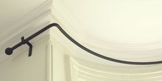 an iron hook is attached to the corner of a white wall with drapes on it