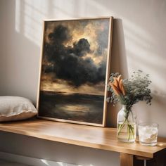 a painting sitting on top of a wooden shelf next to a vase filled with flowers