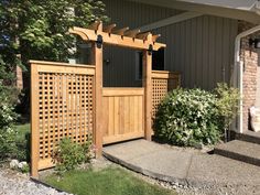 a wooden gate in front of a house with flowers and bushes around the entrance area