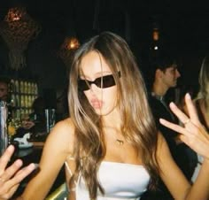 a woman wearing sunglasses making a face while standing in front of other people at a party