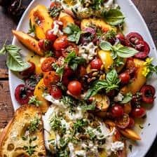 a white plate topped with lots of food on top of a wooden table next to bread