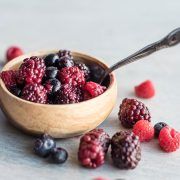 berries and raspberries in a wooden bowl with a spoon