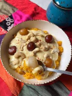 a white bowl filled with food on top of a colorful table cloth next to a blue pot