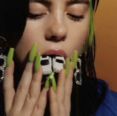 a woman with green nail polish holding her hands to her mouth