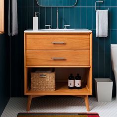 a bathroom with blue tiled walls and white fixtures, including a wooden vanity sink cabinet