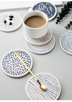 coffee cup and saucer sitting on top of coasters with gold spoon in the middle