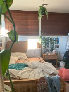 an unmade bed sitting next to a window in a bedroom