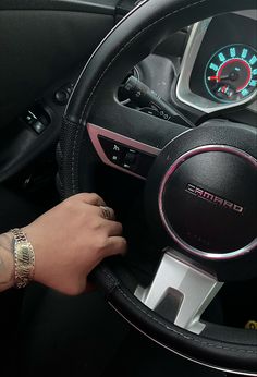 a person is holding the steering wheel and pressing buttons on their car's dashboard