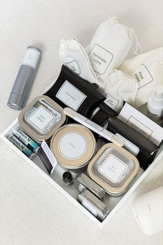 the contents of a personal care kit are neatly organized in a white box on a bed