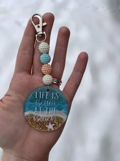 a hand holding a keychain that says, life is better at the beach