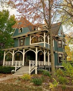 a large green and white house in the fall