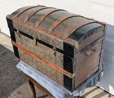 an old trunk sitting on top of a wooden table in front of a garage door