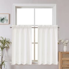 a window with white curtains in front of it and a potted plant next to the window