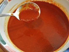 a spoon full of tomato soup in a bowl