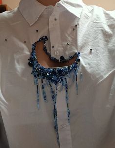 a white shirt with blue beads on it