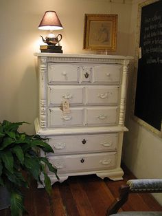 a white dresser sitting next to a green plant