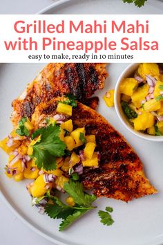 grilled mahi mahi with pineapple salsa on a white plate next to a bowl of mango salsa