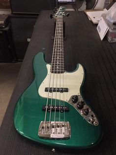 a green bass guitar sitting on top of a table