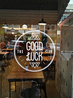 a restaurant window with the words good luck etched into it's glass and people sitting at tables in the background