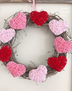 a valentine's day wreath made out of yarn with pink and red hearts on it