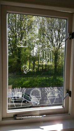 a window with drawings drawn on it and trees in the background