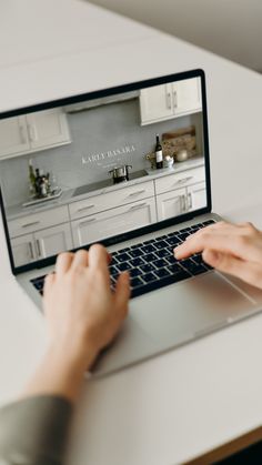 a person using a laptop computer on a white table in front of a kitchen counter