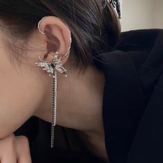 a woman wearing an ear cuff with a dragon on it's back and a chain attached to the side