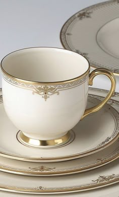 there is a cup and saucer set on the plate with gold trimmings